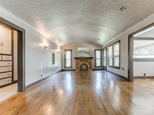 2420 NW 21st St, Oklahoma City, OK 73107 - unfurnished living room with light wood finished floors, a brick fireplace, and vaulted ceiling