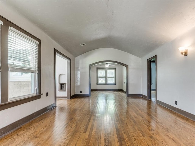 2420 NW 21st St, Oklahoma City, OK 73107 - unfurnished living room with arched walkways, hardwood / wood-style flooring, vaulted ceiling, and ceiling fan