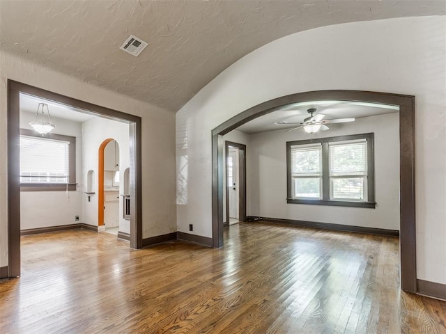 2420 NW 21st St, Oklahoma City, OK 73107 - unfurnished room featuring arched walkways, healthy amount of natural light, ceiling fan, wood finished floors, and vaulted ceiling