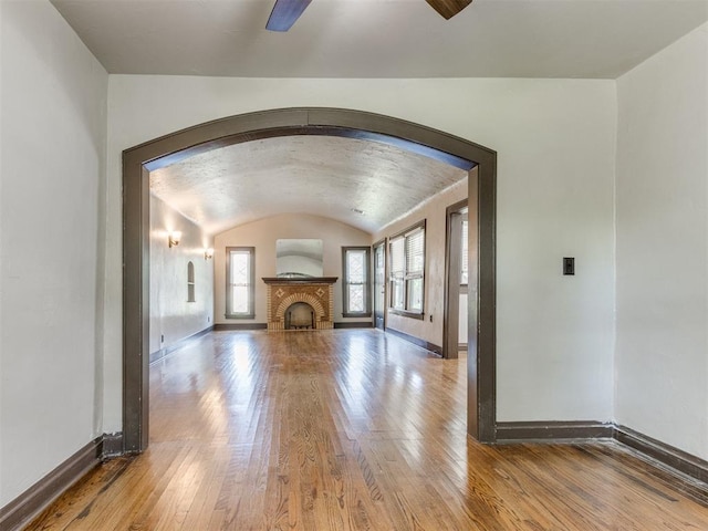 2420 NW 21st St, Oklahoma City, OK 73107 - unfurnished living room featuring wood-type flooring, arched walkways, lofted ceiling, and a fireplace