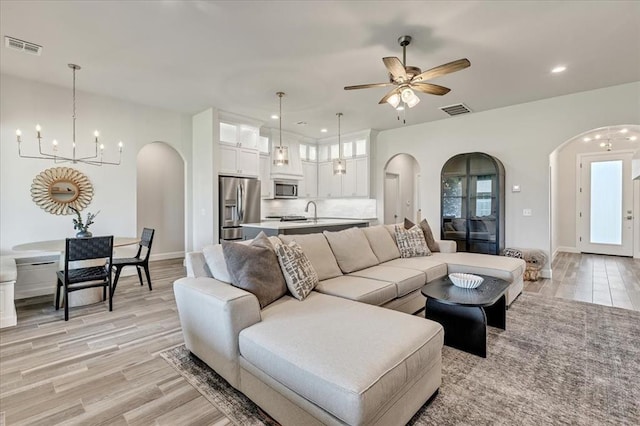 6605 NW 147th St, Oklahoma City, OK 73013 - living room featuring arched walkways, a chandelier, a ceiling fan, recessed lighting, and light wood finished floors