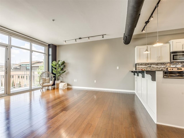 1 NE 2nd St Unit 309, Oklahoma City, OK 73104 - kitchen with track lighting, stainless steel appliances, dark countertops, decorative backsplash, and expansive windows