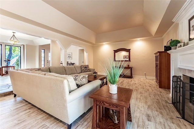 1600 Turtlecreek Rd, Edmond, OK 73013 - living room with arched walkways, a tray ceiling, a tile fireplace, and light wood finished floors