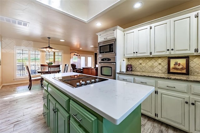 1600 Turtlecreek Rd, Edmond, OK 73013 - kitchen with stainless steel appliances, green cabinetry, white cabinets, light wood-style floors, and backsplash