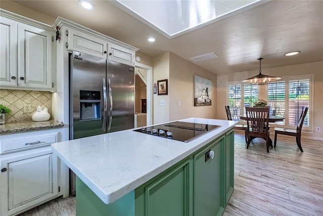 1600 Turtlecreek Rd, Edmond, OK 73013 - kitchen featuring black electric cooktop, stainless steel fridge, a center island, light wood-style floors, and decorative backsplash