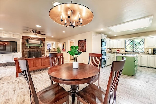 1600 Turtlecreek Rd, Edmond, OK 73013 - dining area with ceiling fan, light wood-type flooring, a stone fireplace, recessed lighting, and a chandelier