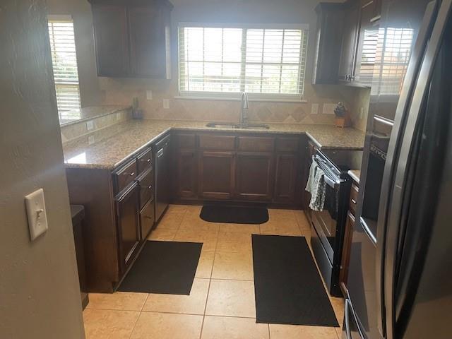 11820 SW 8th St, Yukon, OK 73099 - kitchen featuring appliances with stainless steel finishes, light tile patterned floors, decorative backsplash, and light stone countertops