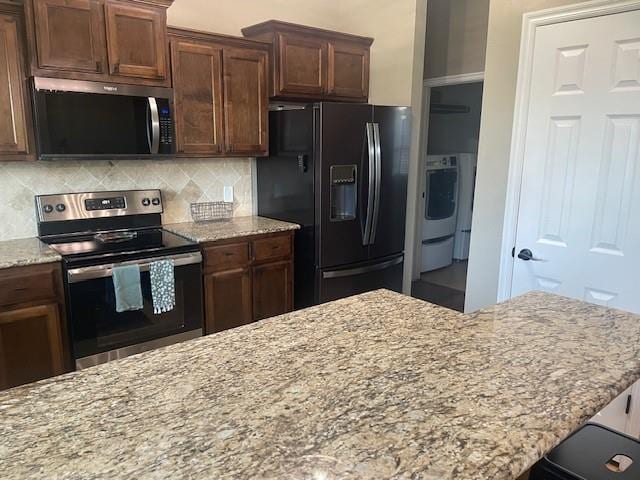 11820 SW 8th St, Yukon, OK 73099 - kitchen with stainless steel electric range oven, black refrigerator with ice dispenser, light stone counters, tasteful backsplash, and washer / clothes dryer