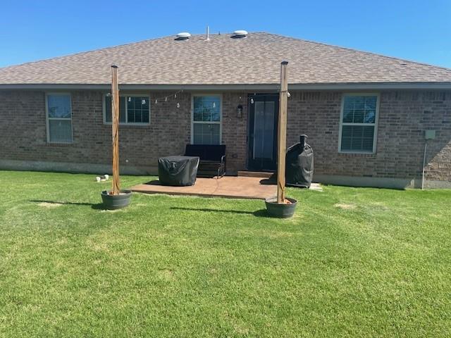 11820 SW 8th St, Yukon, OK 73099 - back of house featuring brick siding, roof with shingles, and a lawn