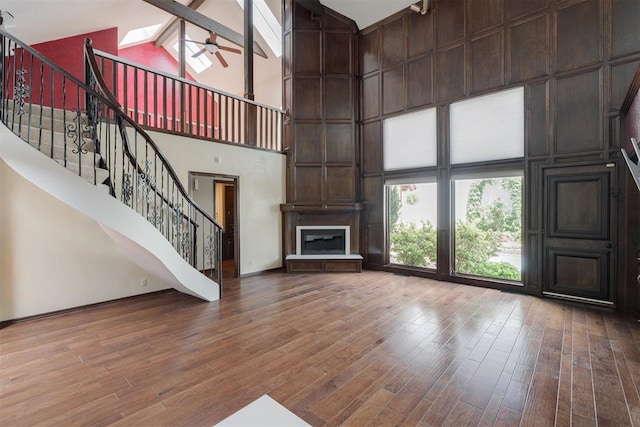 1615 Fox Hollow Rdg, Oklahoma City, OK 73131 - unfurnished living room with high vaulted ceiling, wood finished floors, stairs, ceiling fan, and a fireplace