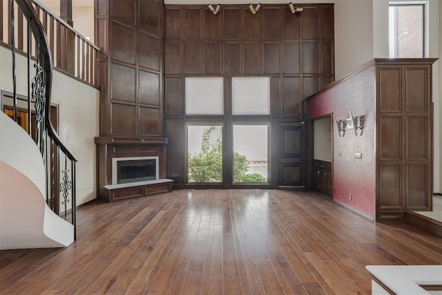 1615 Fox Hollow Rdg, Oklahoma City, OK 73131 - unfurnished living room featuring a towering ceiling, wood-type flooring, stairs, and a large fireplace