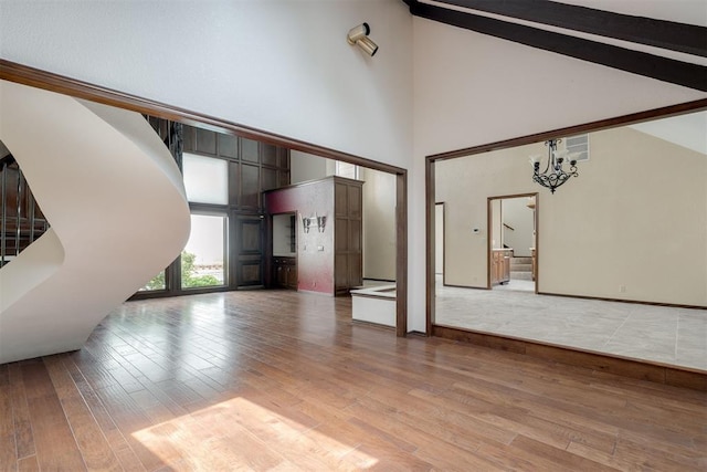 1615 Fox Hollow Rdg, Oklahoma City, OK 73131 - unfurnished living room with high vaulted ceiling, hardwood / wood-style floors, a chandelier, and beam ceiling