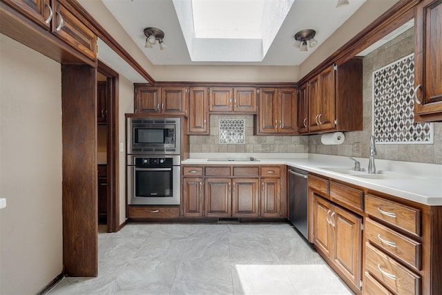 1615 Fox Hollow Rdg, Oklahoma City, OK 73131 - kitchen featuring appliances with stainless steel finishes, a skylight, light countertops, a tray ceiling, and brown cabinets