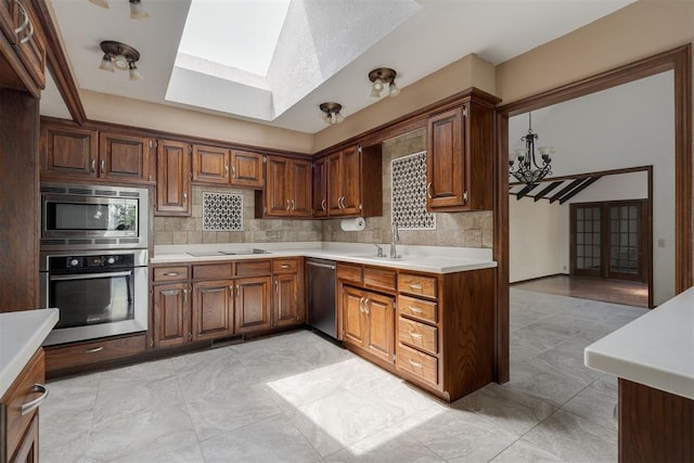 1615 Fox Hollow Rdg, Oklahoma City, OK 73131 - kitchen with stainless steel appliances, a skylight, light countertops, tasteful backsplash, and a chandelier
