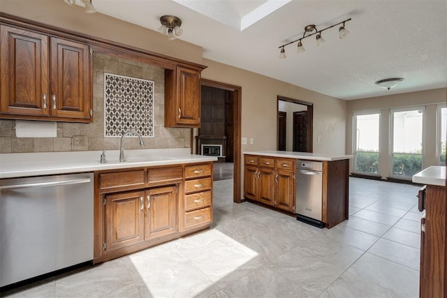 1615 Fox Hollow Rdg, Oklahoma City, OK 73131 - kitchen featuring stainless steel dishwasher, brown cabinetry, light countertops, and rail lighting