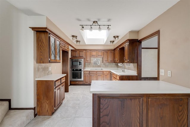 1615 Fox Hollow Rdg, Oklahoma City, OK 73131 - kitchen with stainless steel appliances, a skylight, decorative backsplash, light countertops, and light tile patterned flooring
