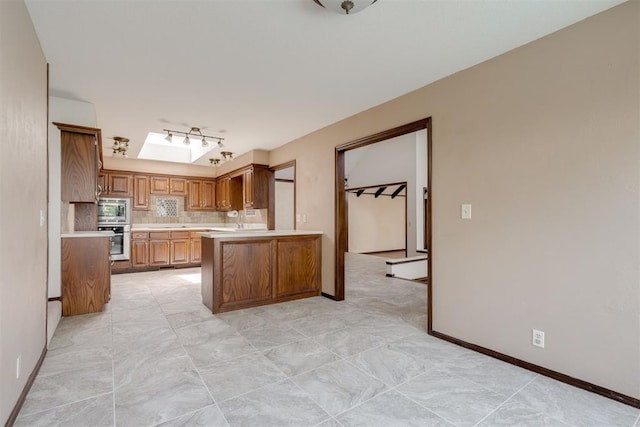 1615 Fox Hollow Rdg, Oklahoma City, OK 73131 - kitchen featuring stainless steel appliances, light countertops, decorative backsplash, brown cabinets, and a peninsula