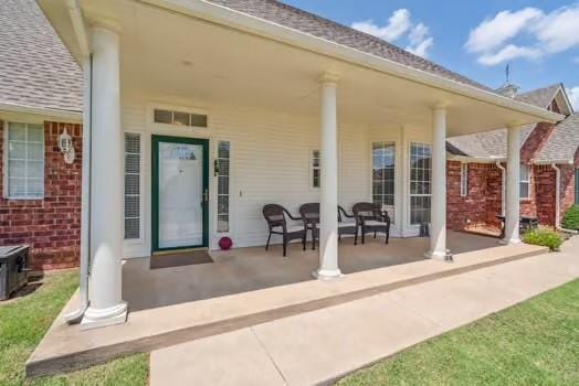 11416 Leslie Beachler Ln, Midwest City, OK 73130 - back of property with covered porch, brick siding, and roof with shingles