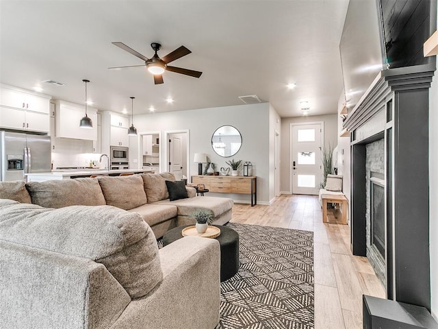 15109 Caspian Ln, Edmond, OK 73013 - living area with a fireplace, light wood-style floors, a ceiling fan, and recessed lighting