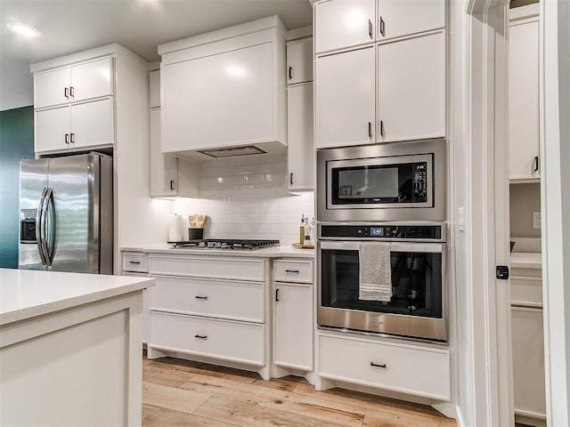 15109 Caspian Ln, Edmond, OK 73013 - kitchen with stainless steel appliances, light countertops, light wood-type flooring, and decorative backsplash