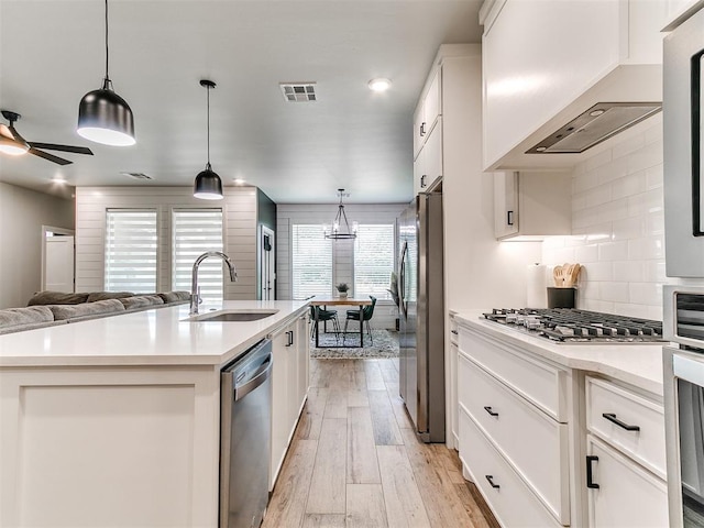 15109 Caspian Ln, Edmond, OK 73013 - kitchen with appliances with stainless steel finishes, premium range hood, backsplash, light wood finished floors, and light countertops