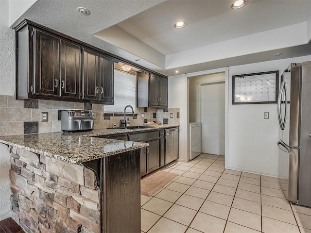 1008 S Neptune Rd, Edmond, OK 73003 - kitchen with stainless steel appliances, a breakfast bar area, a peninsula, light stone counters, and backsplash