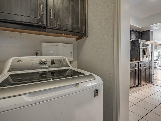 1008 S Neptune Rd, Edmond, OK 73003 - laundry room with washer / dryer, cabinet space, light tile patterned floors, and a textured wall