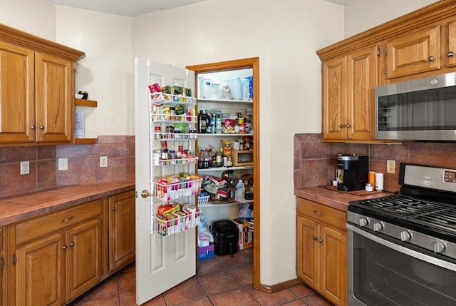 125 NW 147th St, Edmond, OK 73013 - kitchen featuring appliances with stainless steel finishes, tile patterned flooring, and tasteful backsplash