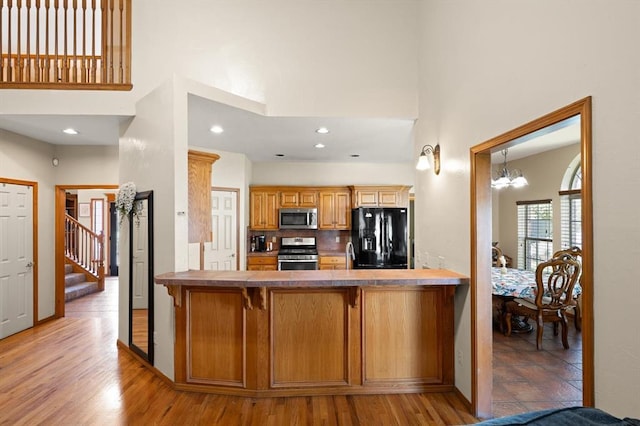125 NW 147th St, Edmond, OK 73013 - kitchen with stainless steel appliances, a high ceiling, a peninsula, a chandelier, and a kitchen bar