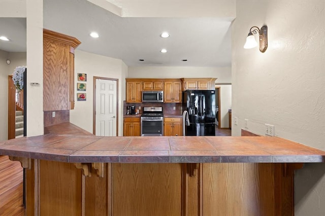 125 NW 147th St, Edmond, OK 73013 - kitchen with appliances with stainless steel finishes, a peninsula, recessed lighting, brown cabinets, and a kitchen breakfast bar