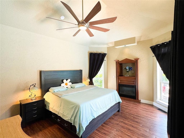 1004 Reginald Dr, Norman, OK 73072 - bedroom with wood finished floors, multiple windows, a ceiling fan, and a fireplace