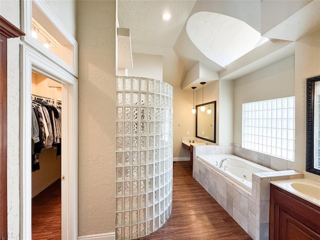 1004 Reginald Dr, Norman, OK 73072 - full bathroom featuring a whirlpool tub, a textured wall, wood finished floors, vanity, and a spacious closet