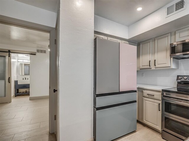 11550 N May Ave Unit 108, Oklahoma City, OK 73120 - kitchen featuring appliances with stainless steel finishes, light countertops, tasteful backsplash, a barn door, and recessed lighting