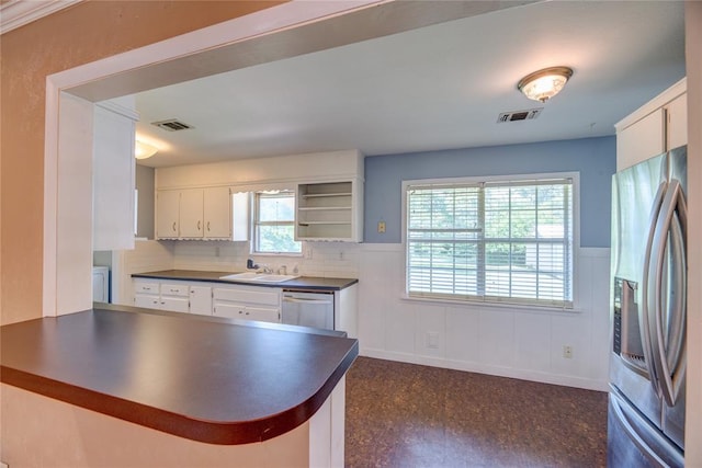 824 N Poplar Ln, Midwest City, OK 73130 - kitchen featuring stainless steel appliances, dark countertops, wainscoting, a peninsula, and white cabinets