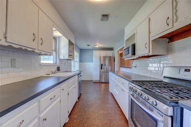 824 N Poplar Ln, Midwest City, OK 73130 - kitchen featuring appliances with stainless steel finishes, white cabinets, dark countertops, wainscoting, and backsplash