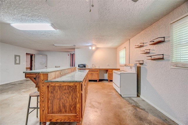 824 N Poplar Ln, Midwest City, OK 73130 - kitchen featuring concrete floors, a kitchen bar, a textured wall, a textured ceiling, and a kitchen island