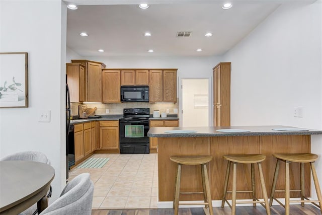 825 Elm Ave, Yukon, OK 73099 - kitchen with black appliances, a breakfast bar area, dark countertops, decorative backsplash, and recessed lighting