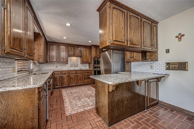1504 Canary Pl, Edmond, OK 73034 - kitchen with a peninsula, appliances with stainless steel finishes, brick flooring, light stone counters, and recessed lighting