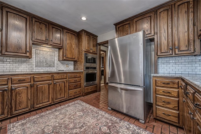 1504 Canary Pl, Edmond, OK 73034 - kitchen featuring stainless steel appliances, brick floors, decorative backsplash, light stone counters, and recessed lighting