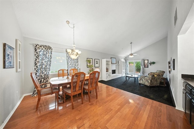 4713 N Cypress Ct, Oklahoma City, OK 73162 - dining room with a fireplace, ceiling fan, light wood-type flooring, a chandelier, and high vaulted ceiling