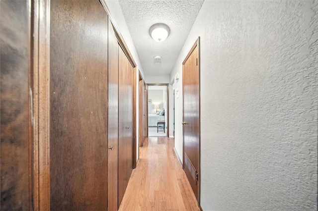 4713 N Cypress Ct, Oklahoma City, OK 73162 - hallway featuring light wood-type flooring, a textured ceiling, and a textured wall