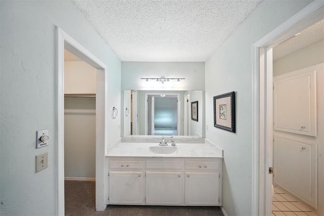 4713 N Cypress Ct, Oklahoma City, OK 73162 - bathroom featuring a textured ceiling, vanity, tile patterned floors, and a walk in closet