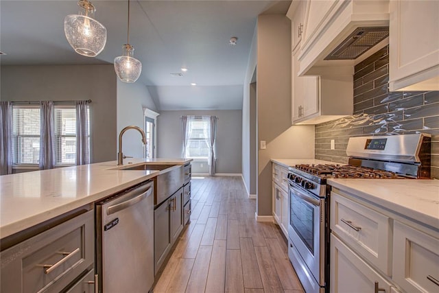 3800 Palmetto Trl, Oklahoma City, OK 73179 - kitchen with appliances with stainless steel finishes, premium range hood, light wood-type flooring, hanging light fixtures, and white cabinetry