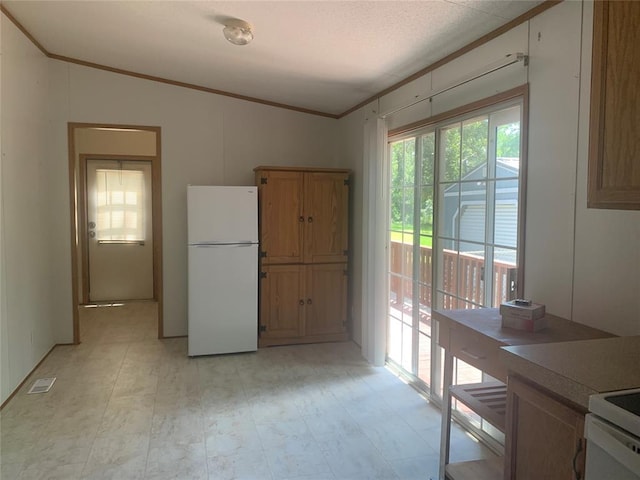 128 N Buffalo St, Canadian, OK 74425 - kitchen featuring freestanding refrigerator, ornamental molding, vaulted ceiling, light countertops, and brown cabinetry