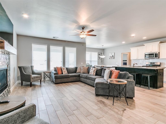1417 Atalon Dr, Moore, OK 73160 - living area featuring ceiling fan, light wood-style flooring, a glass covered fireplace, and recessed lighting