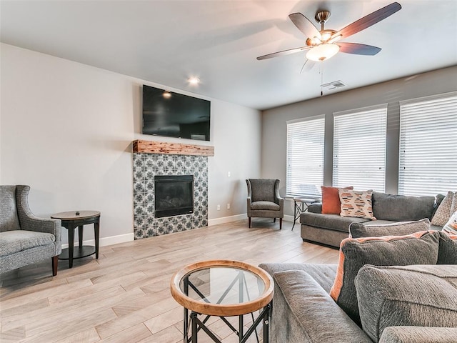 1417 Atalon Dr, Moore, OK 73160 - living room with ceiling fan, a tile fireplace, and light wood-style flooring