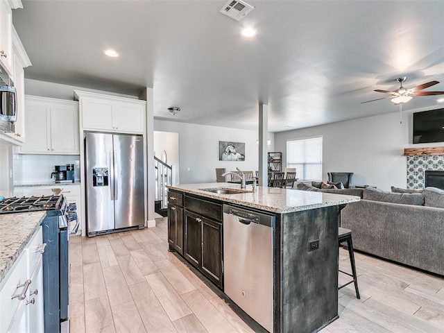 1417 Atalon Dr, Moore, OK 73160 - kitchen with stainless steel appliances, a ceiling fan, open floor plan, a kitchen breakfast bar, and white cabinetry