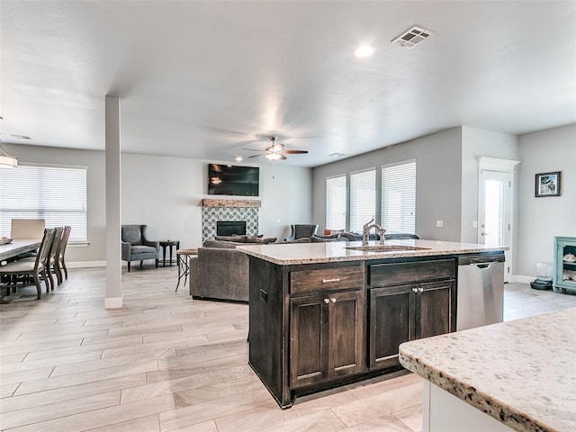 1417 Atalon Dr, Moore, OK 73160 - kitchen with stainless steel dishwasher, a fireplace, a ceiling fan, an island with sink, and open floor plan
