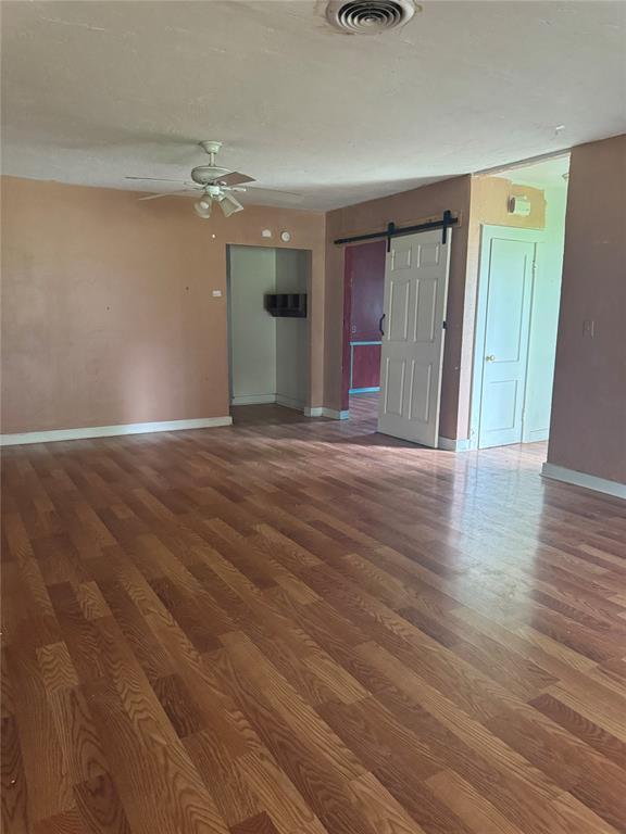 201 S Oak St, Pauls Valley, OK 73075 - spare room with a barn door, ceiling fan, and wood finished floors