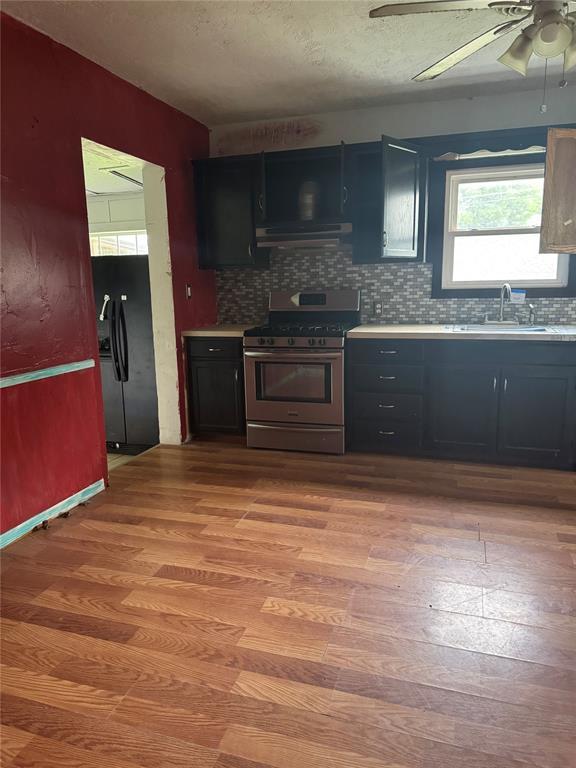 201 S Oak St, Pauls Valley, OK 73075 - kitchen with stainless steel gas range, freestanding refrigerator, backsplash, light wood-style flooring, and ceiling fan